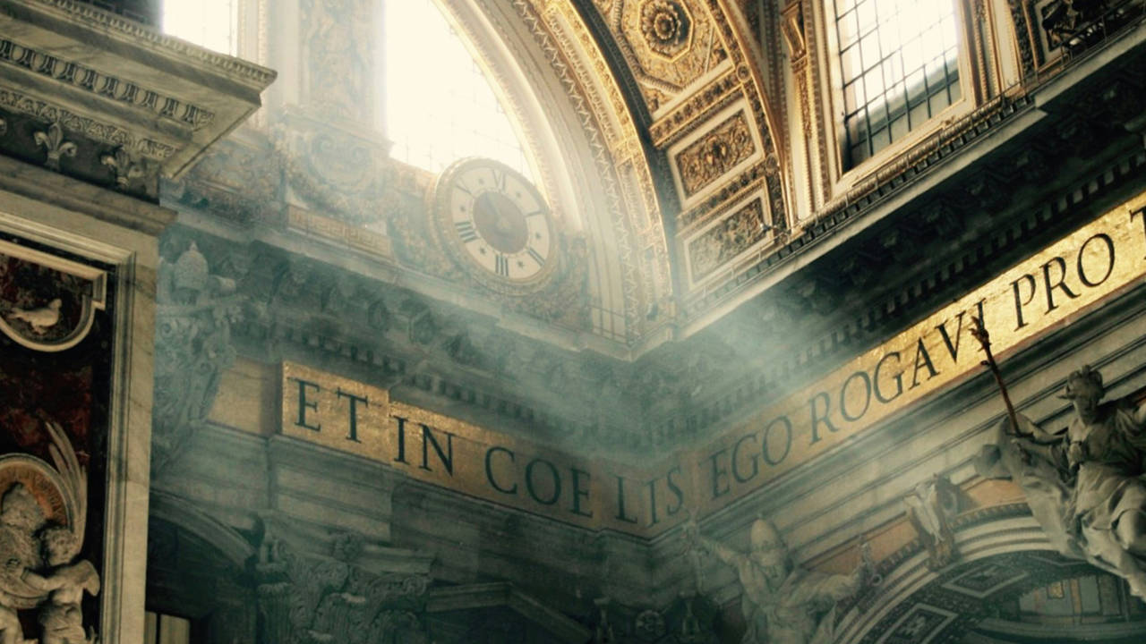 Rays of sunlight enter through the windows of St. Peter's Basilica in Vatican City, illuminating its interior and a wall containing a phrase in Latin.