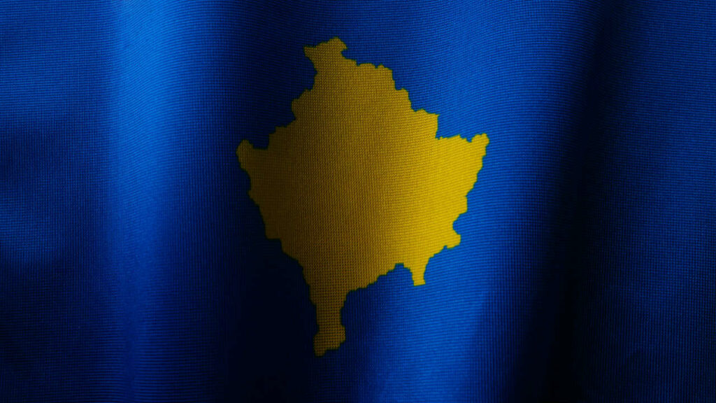 Un dettaglio della bandiera del Kosovo, in cui compare la forma del Paese in giallo su sfondo blu.